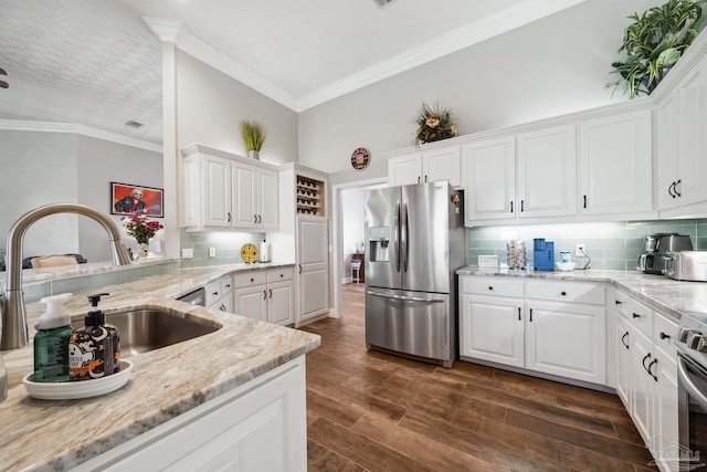 1328 Tour Dr, Gulf Breeze, FL 32563 - kitchen with stainless steel appliances, a sink, white cabinets, light stone counters, and ornamental molding
