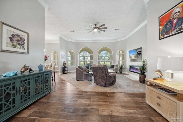 1328 Tour Dr, Gulf Breeze, FL 32563 - living room with crown molding, ceiling fan, a glass covered fireplace, dark wood-type flooring, and baseboards