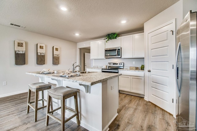 6340 Firefly Dr, Milton, FL 32583 - kitchen featuring a textured ceiling, appliances with stainless steel finishes, visible vents, and light wood-style floors