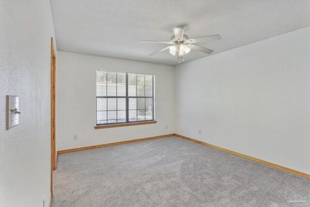 spare room featuring ceiling fan, light colored carpet, and a textured ceiling