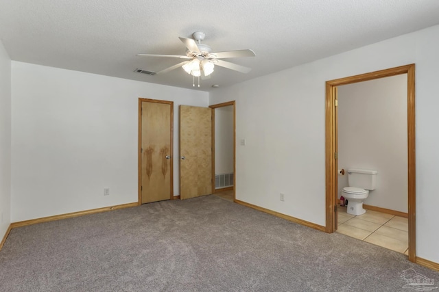 unfurnished bedroom featuring ceiling fan, light colored carpet, connected bathroom, and a textured ceiling