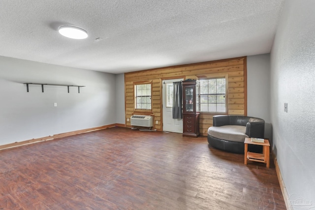 sitting room featuring a wall mounted air conditioner, dark hardwood / wood-style floors, and a textured ceiling