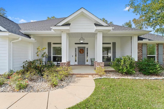 entrance to property with a yard and covered porch