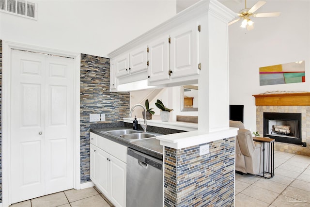 kitchen featuring dishwasher, white cabinetry, sink, and a tiled fireplace