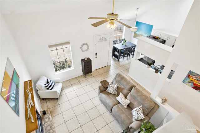 tiled living room with ceiling fan and high vaulted ceiling