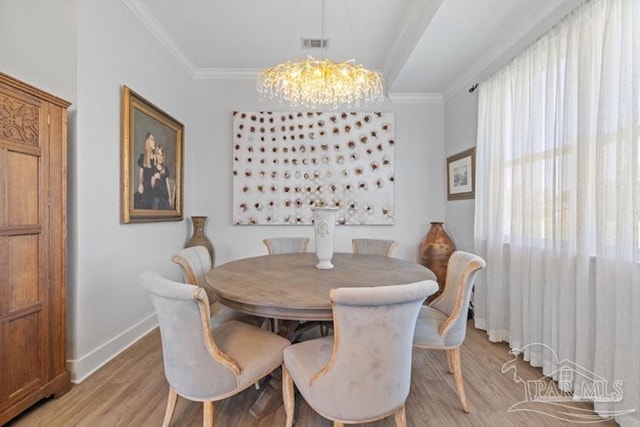 dining area featuring light hardwood / wood-style floors, crown molding, and a notable chandelier