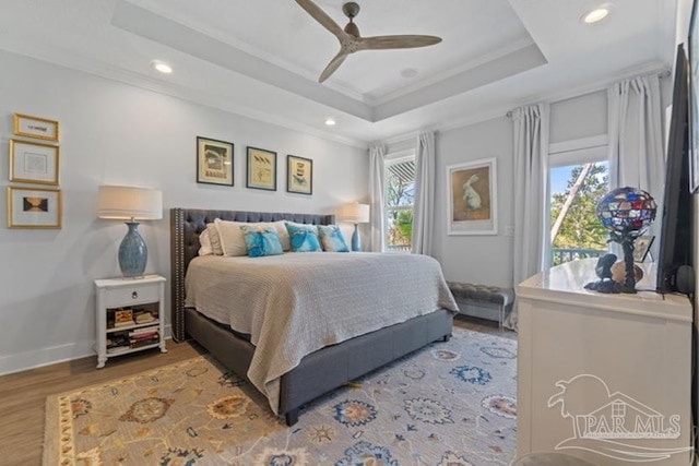 bedroom featuring a tray ceiling, ceiling fan, crown molding, and hardwood / wood-style flooring