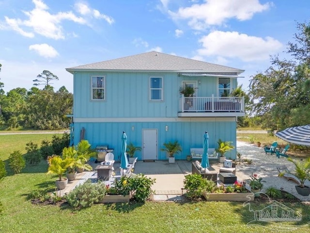 rear view of house with an outdoor living space, a patio area, a yard, and a balcony