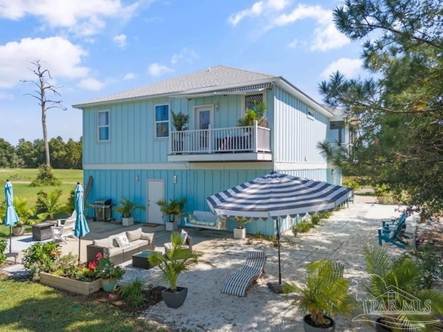 rear view of property featuring outdoor lounge area, a balcony, and a patio