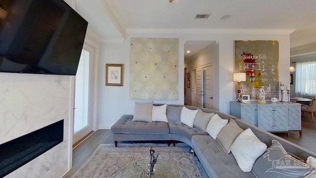 living room with a healthy amount of sunlight, ornamental molding, and hardwood / wood-style flooring