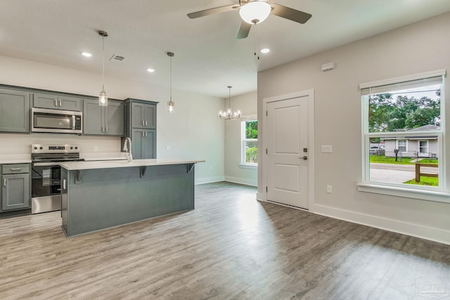 kitchen featuring a center island with sink, plenty of natural light, stainless steel appliances, and hanging light fixtures