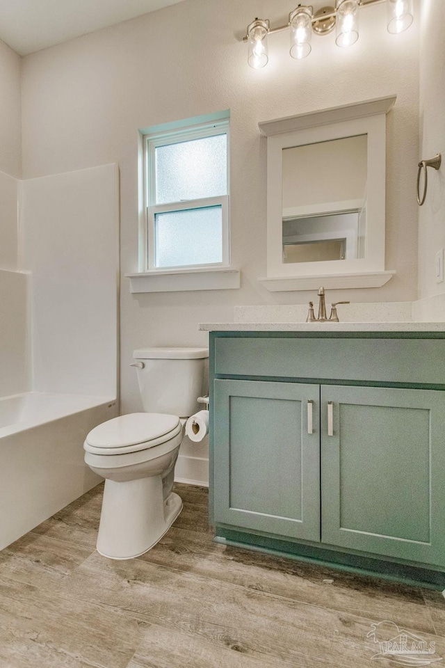 full bathroom with shower / tub combination, vanity, hardwood / wood-style flooring, and toilet