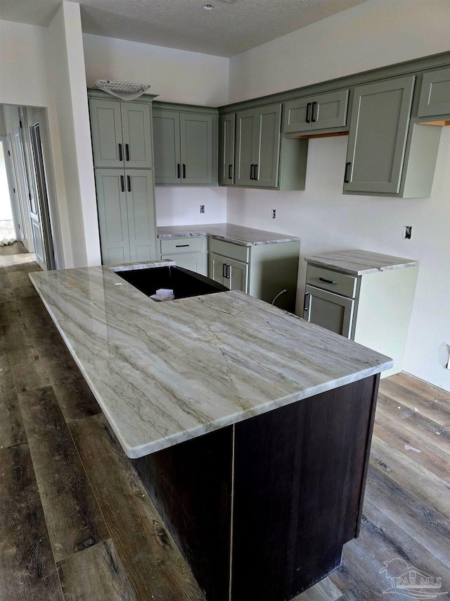 kitchen featuring dark wood-type flooring, a kitchen island, and light stone countertops