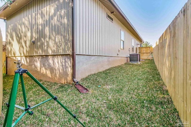 view of property exterior featuring central AC, a lawn, and fence