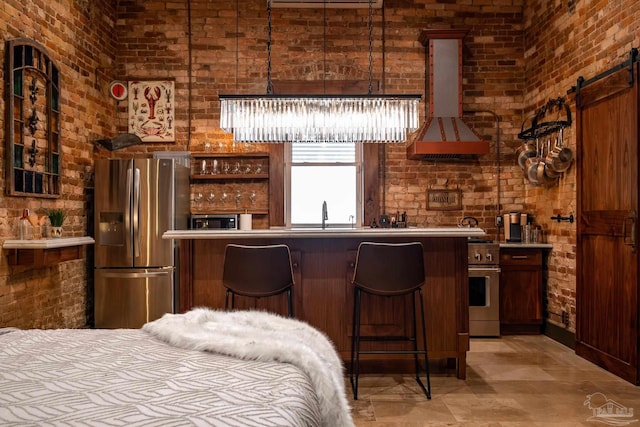 interior space featuring a barn door, extractor fan, brick wall, and appliances with stainless steel finishes