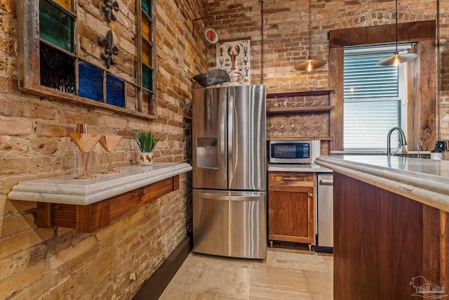 kitchen featuring decorative light fixtures, brick wall, and appliances with stainless steel finishes