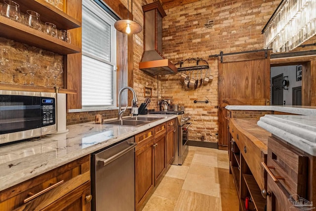 kitchen with sink, a barn door, brick wall, light tile patterned floors, and appliances with stainless steel finishes