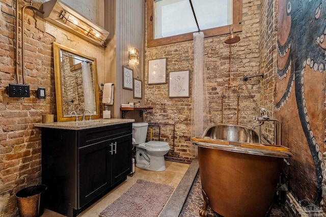 bathroom featuring a towering ceiling, vanity, brick wall, and toilet