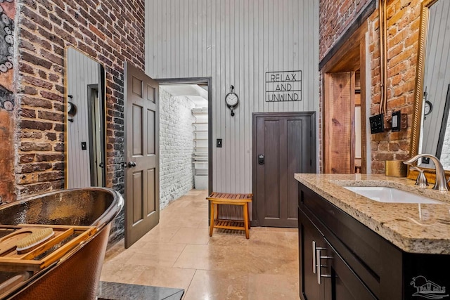 bathroom with brick wall, tile patterned floors, a tub to relax in, wood walls, and vanity