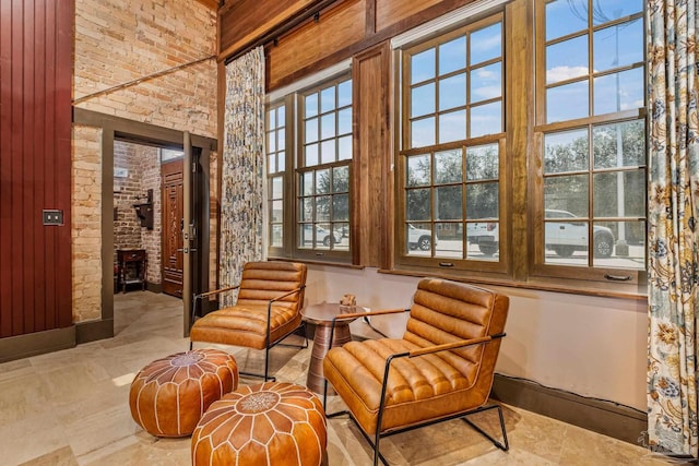 living area featuring brick wall, a towering ceiling, a fireplace, and wooden walls