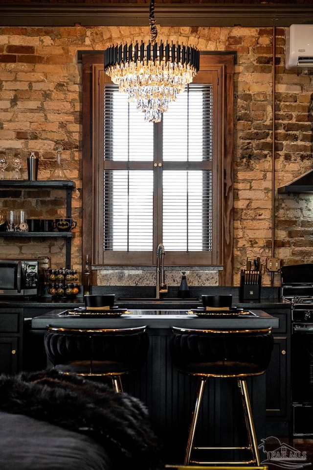 kitchen featuring sink, a wall mounted air conditioner, brick wall, a notable chandelier, and black range