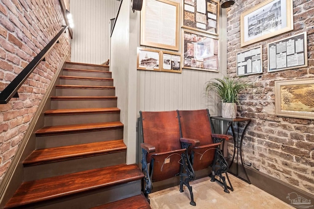 staircase featuring brick wall