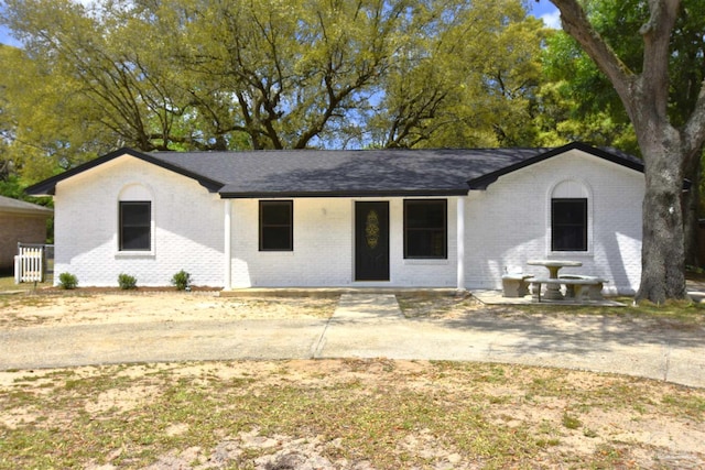 view of front of home featuring brick siding and roof with shingles