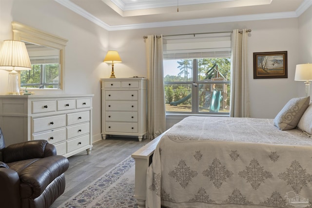 bedroom with ornamental molding, light hardwood / wood-style floors, and a raised ceiling