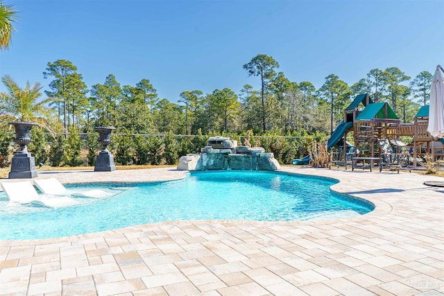 view of swimming pool featuring pool water feature, a playground, and a patio