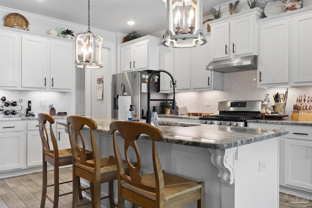 kitchen featuring pendant lighting, stainless steel appliances, a kitchen breakfast bar, white cabinets, and a kitchen island