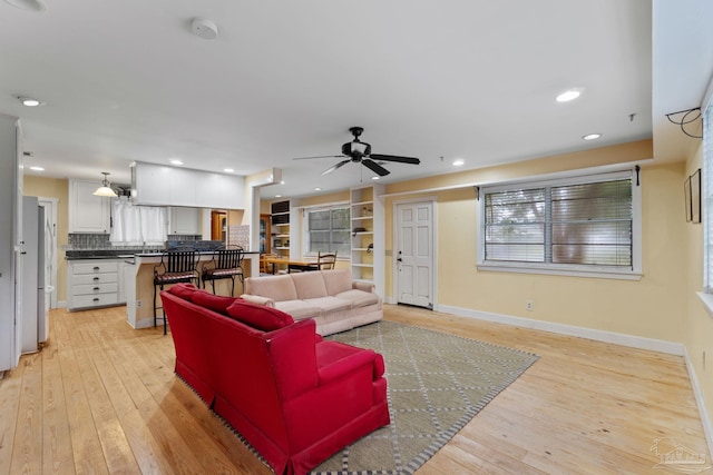 living area featuring light wood-style floors, baseboards, a ceiling fan, and recessed lighting