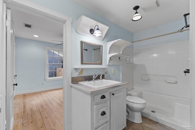 bathroom featuring toilet, vanity, walk in shower, and visible vents