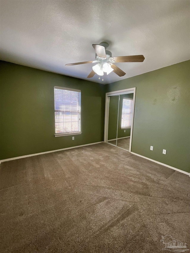 unfurnished bedroom with carpet floors, a closet, a ceiling fan, a textured ceiling, and baseboards