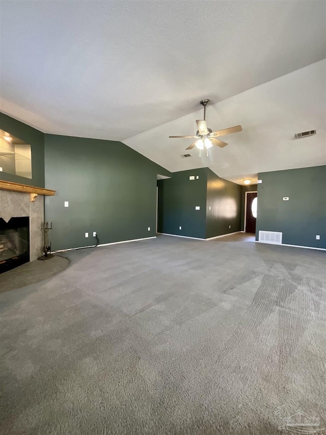 unfurnished living room with carpet floors, visible vents, vaulted ceiling, and a tile fireplace