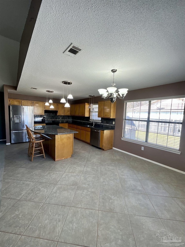 kitchen with a kitchen island, hanging light fixtures, an inviting chandelier, stainless steel appliances, and a sink