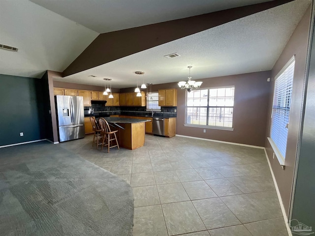 kitchen with visible vents, dark countertops, appliances with stainless steel finishes, a center island, and pendant lighting