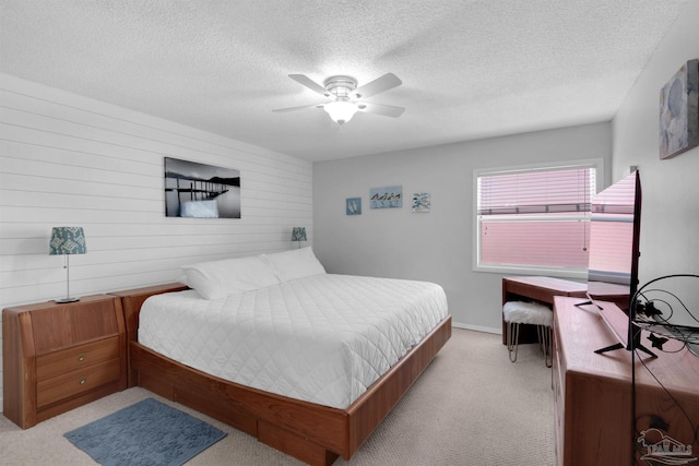 bedroom featuring light carpet, ceiling fan, and a textured ceiling