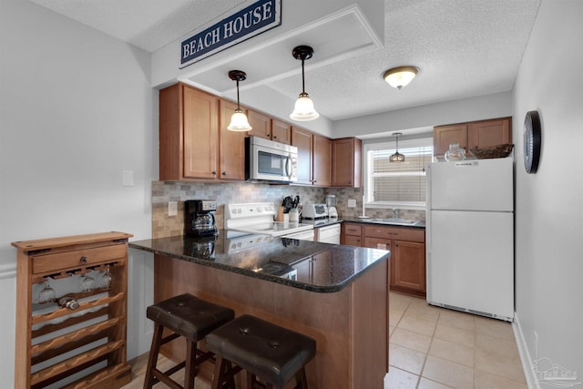 kitchen with a peninsula, white appliances, brown cabinets, and a kitchen breakfast bar