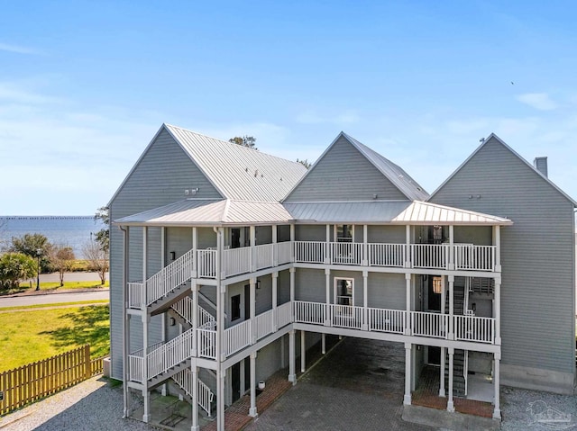 back of property with stairway, metal roof, a balcony, and fence