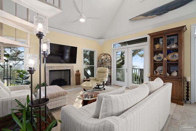 living area with a fireplace with raised hearth, a healthy amount of sunlight, a ceiling fan, and ornamental molding