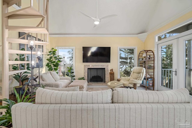 living area with a fireplace with raised hearth, crown molding, a ceiling fan, and vaulted ceiling