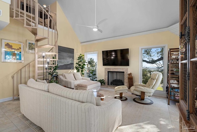 living area featuring stairway, plenty of natural light, a fireplace, and crown molding