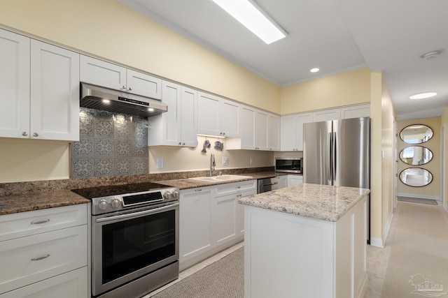 kitchen with under cabinet range hood, stainless steel appliances, white cabinets, and a sink