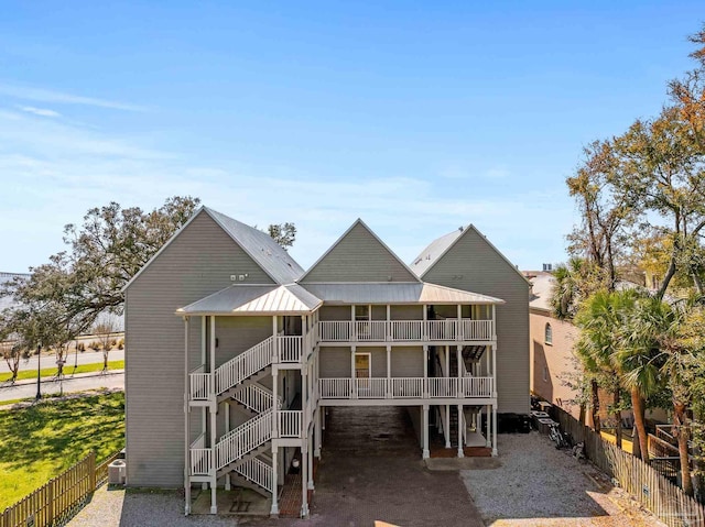 back of house featuring metal roof, stairs, and fence