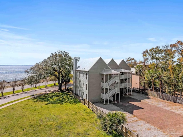 exterior space with a water view, fence, stairway, a sunroom, and metal roof