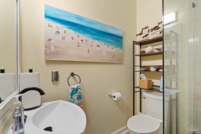 bathroom with toilet, baseboards, and a sink