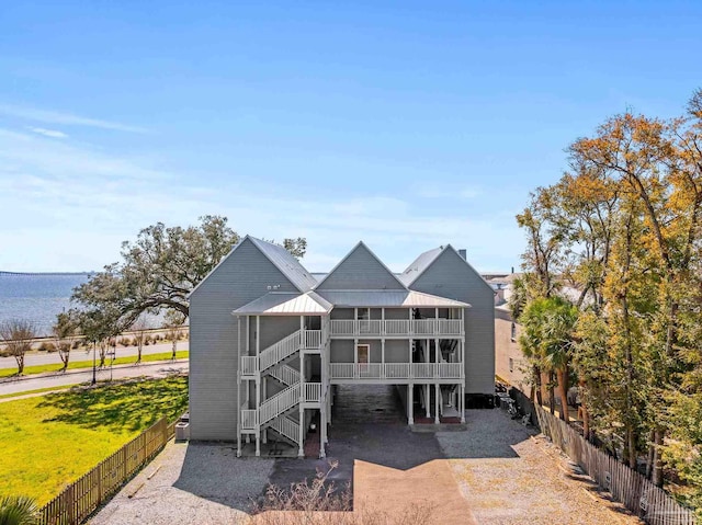 back of house featuring metal roof, fence, stairs, and a sunroom