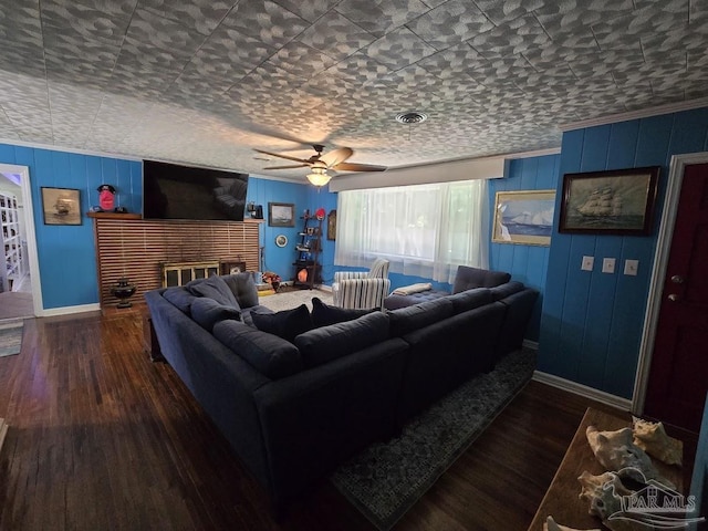 living room with ornamental molding, dark wood-type flooring, ceiling fan, and a fireplace