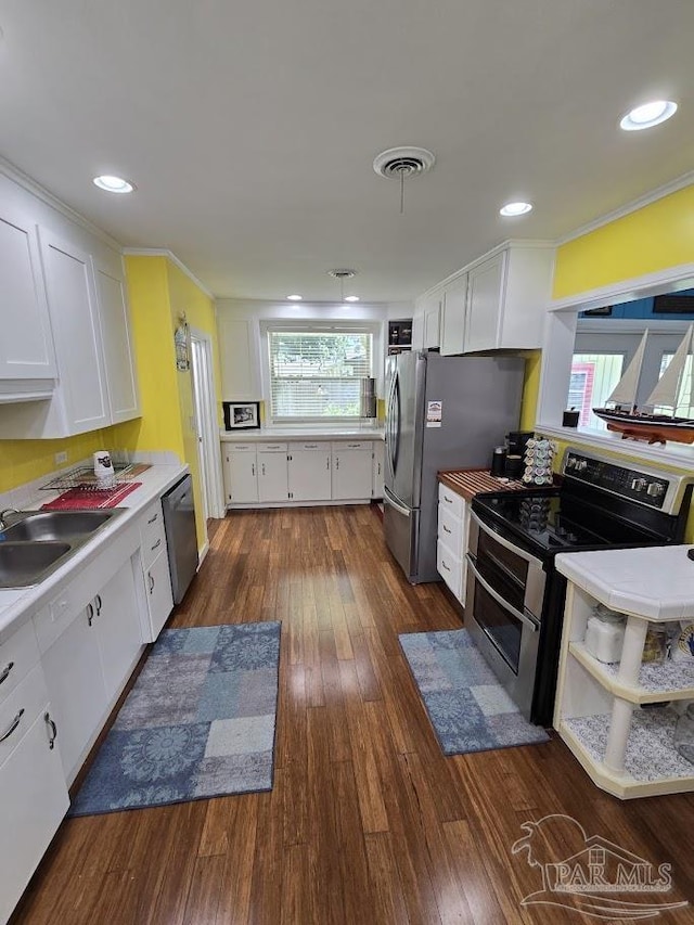 kitchen with sink, white cabinetry, ornamental molding, appliances with stainless steel finishes, and dark hardwood / wood-style flooring