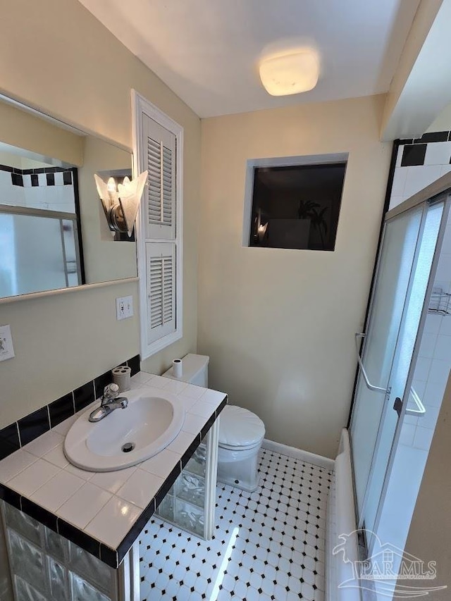 bathroom with vanity, a shower with shower door, and toilet